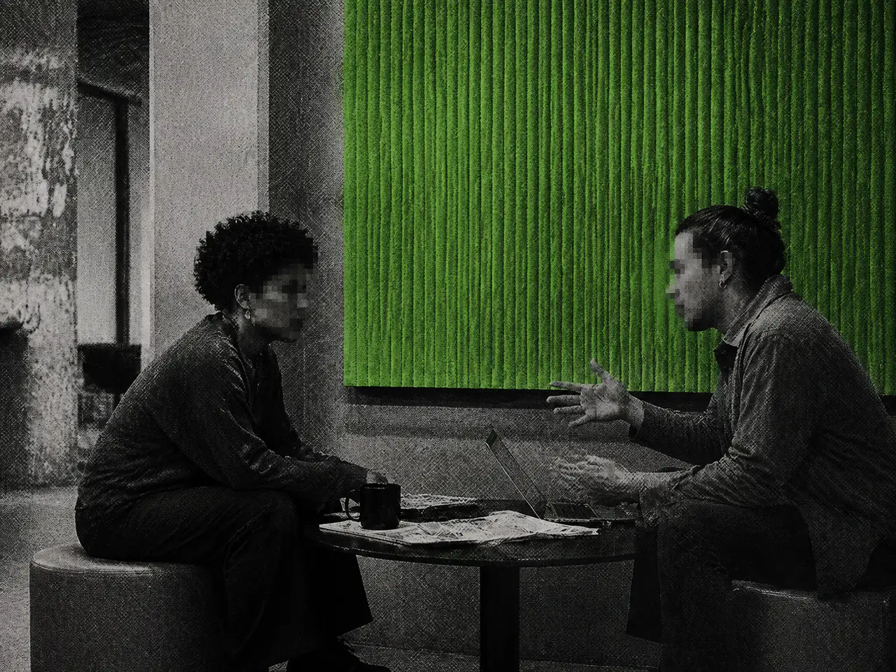 Two people with pixelated faces talk at a table in front of a green acoustic panel.